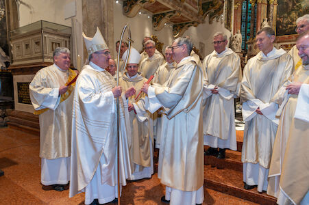 Johannes Chum bekommt eine rote Mappe von Bischof Krautwaschl überreicht