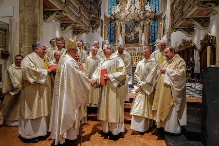 Johannes Chum wird von Bischof Krautwaschl eine rote Mappe überreicht, andere Perspektive