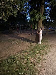 Ein Kind in der Nacht an dem gespannten Seil zwischen zwei Bäumen.